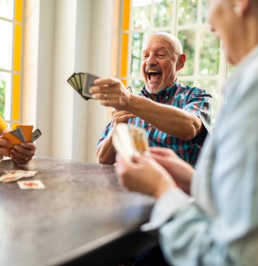 Group of senior friends enjoying while playing cards at home
